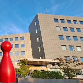 Eine schwarze und eine rote Spielfigur stehen vor dem Kreishaus des Rheinisch-Bergischen Kreises in Bergisch Gladbach-Heidkamp.