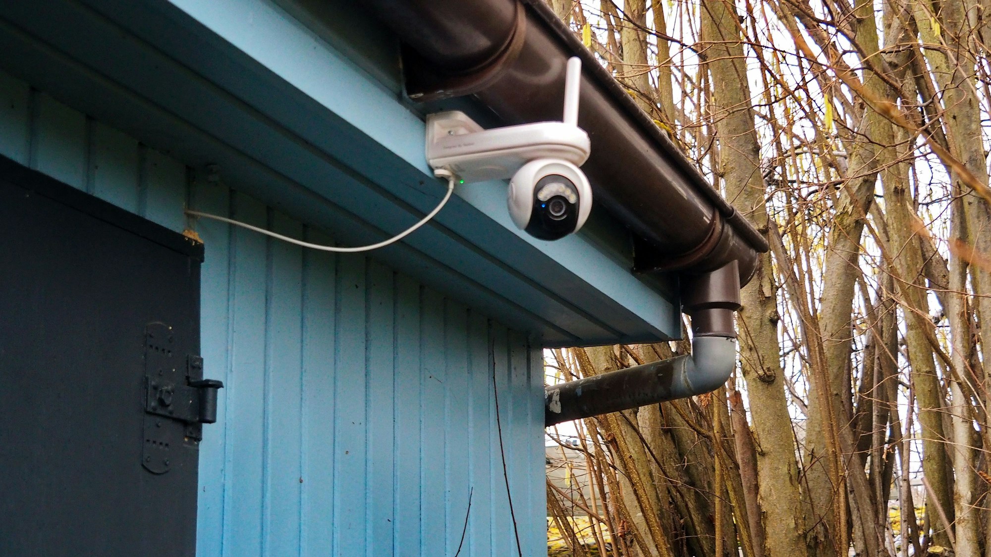 An einer blauen Bretterhütte ist eine Kamera angebracht.