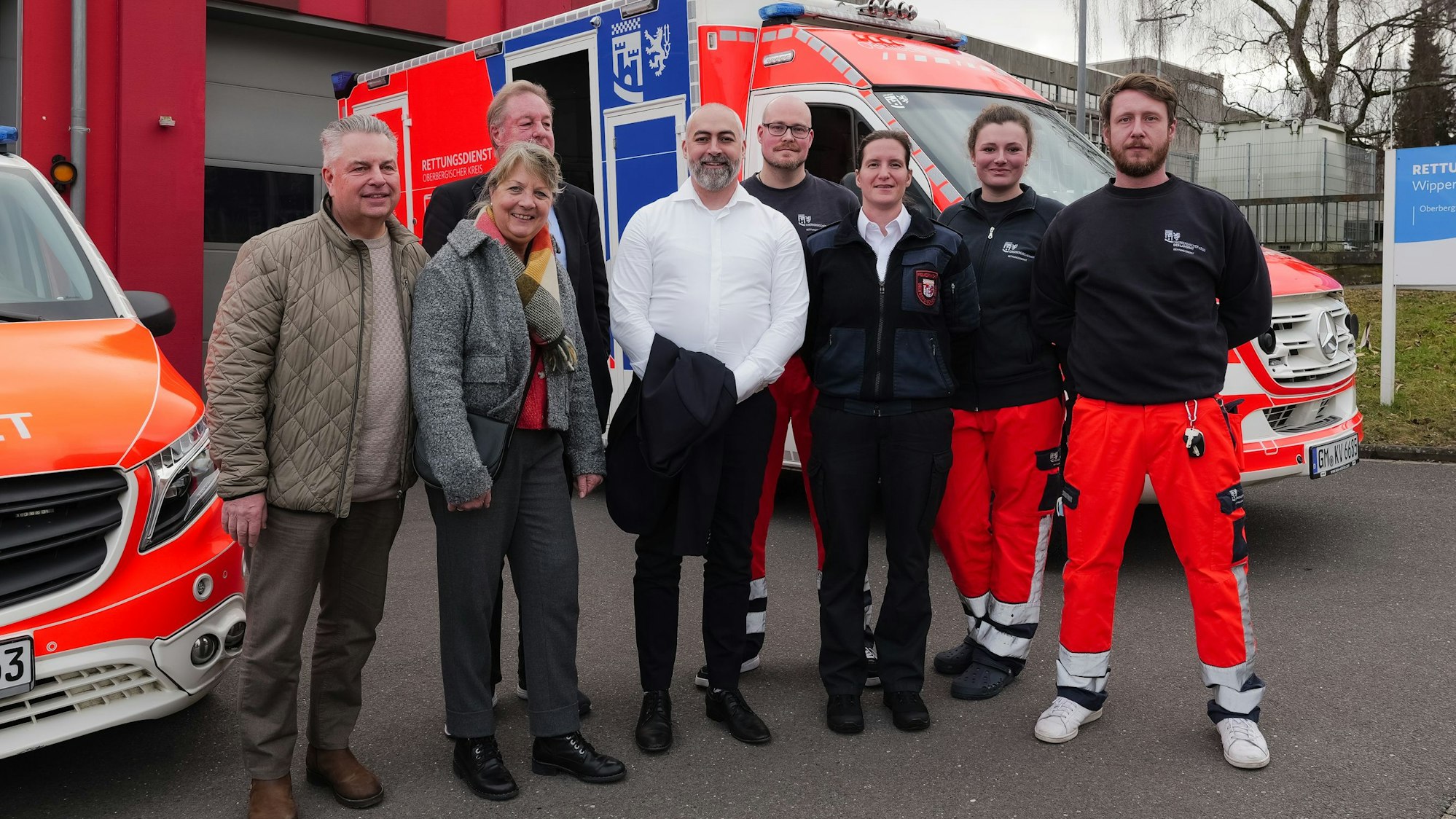 Das Foto zeigt einen Personengruppe und zwei Rettungsfahrzeuge und die Rettungswache im Hintergrund.