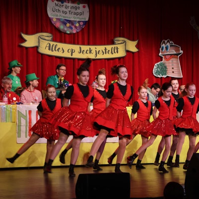 Auf dem Bild sind tanzende Mädchen in roten Kostümen zu sehen.