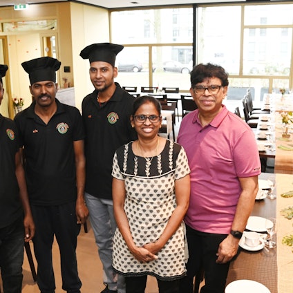 Das Ehepaar Narayanan mit Köchen im neuen Chennai Chef Grand am Melatenfriedhof. Rechts auf dem Bild sieht man die eingedeckte Tafel für die nächsten Trauergesellschaft.