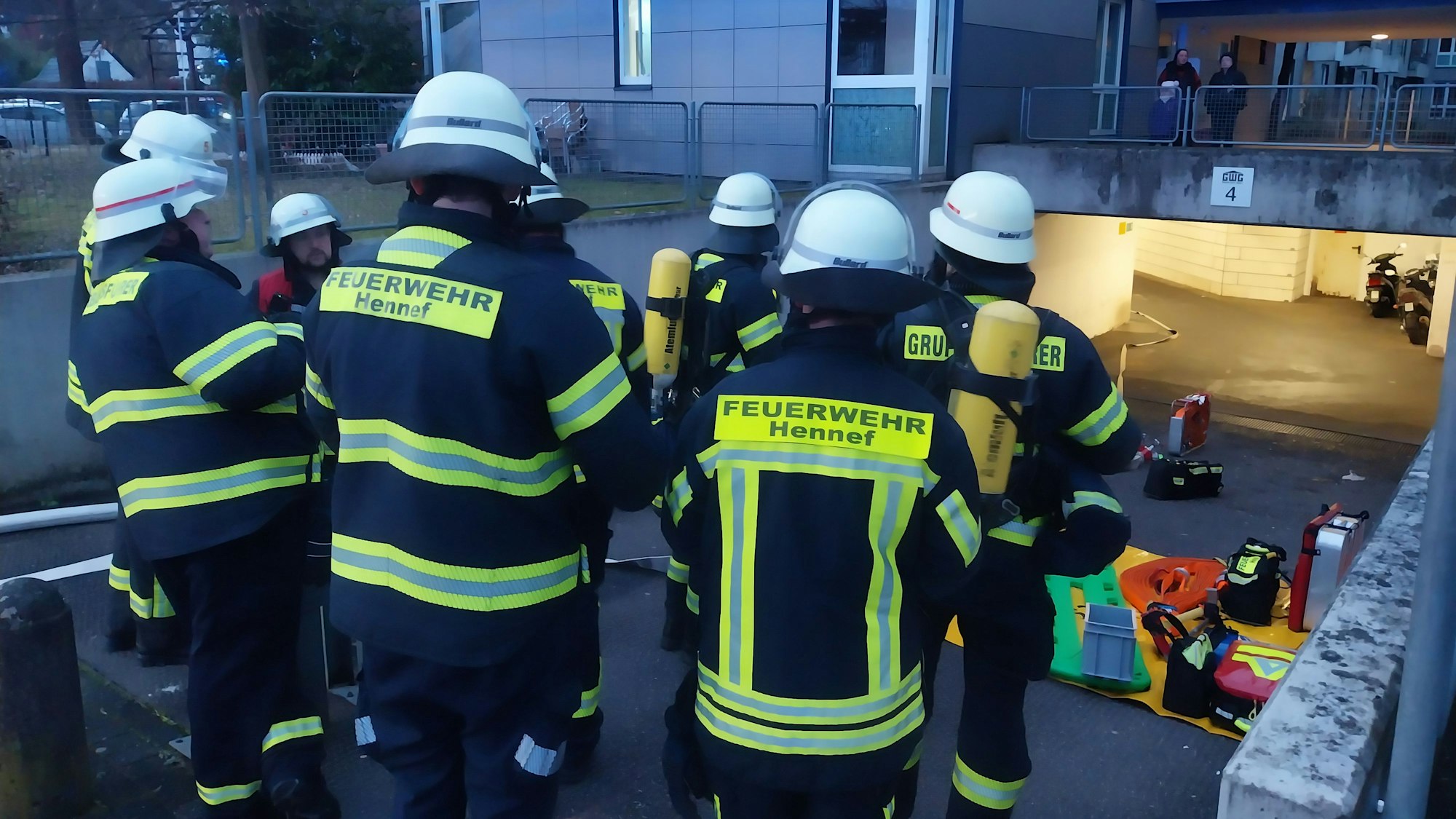 Feuerwehrleute stehen vor der Tiefgarage in der Schubertstraße, aus der Rauch gekommen war.