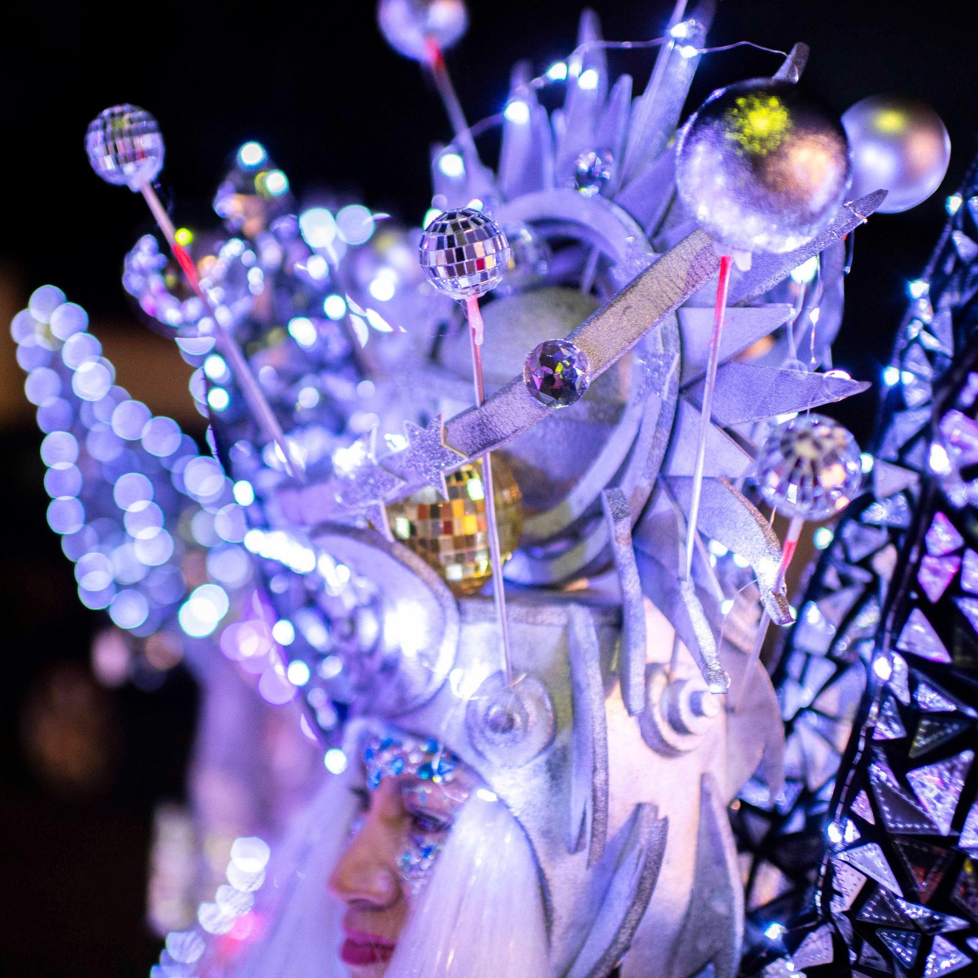 Eine Karnevalistin trägt beim Lichterzug in Eiserfey einen opulenten silbernen Kopfschmuck mit kleinen Discokugeln und vielen Lichtern.
