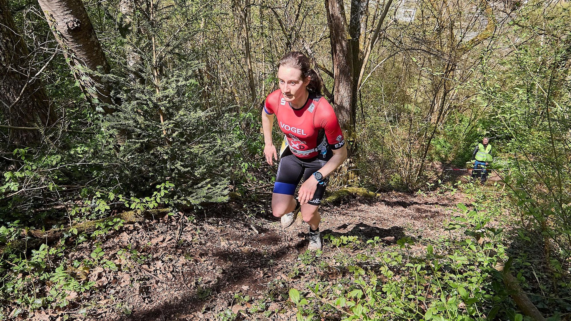 Milena Voge läuft in Sportkleidung ein treppiges Gelände in einem Waldstück hoch.