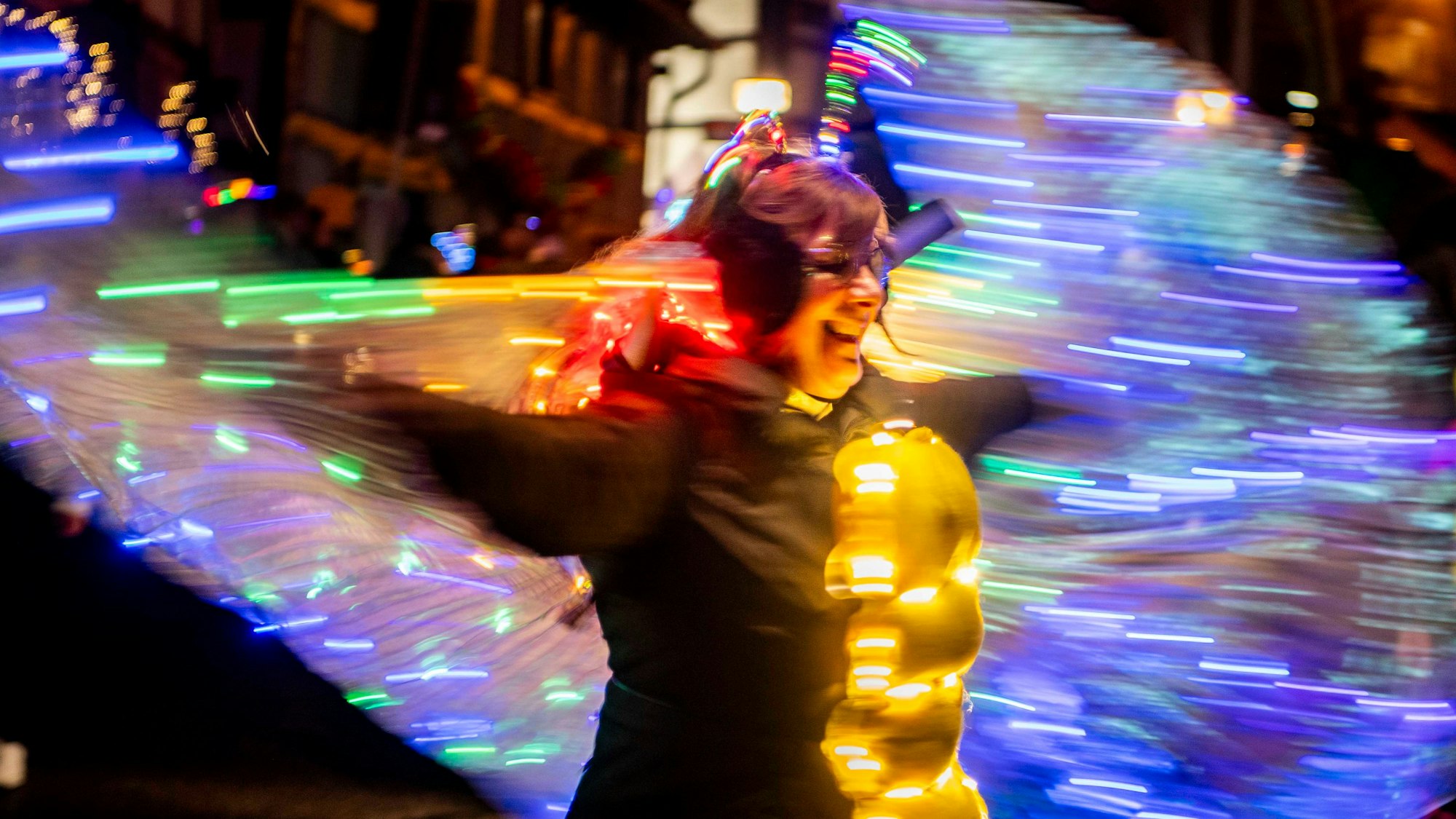 Eine Karnevalistin feiert mit einem mit vielen Lichtern geschmückten Schmetterlingskostüm im Lichterzug in Mechernich-Eiserfey.
