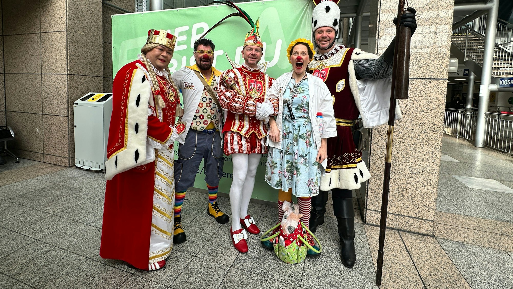 Das Dreigestirn aus Rodenkirchen steht mit zwei Klinik-Clowns im Foyer der Uniklinik.