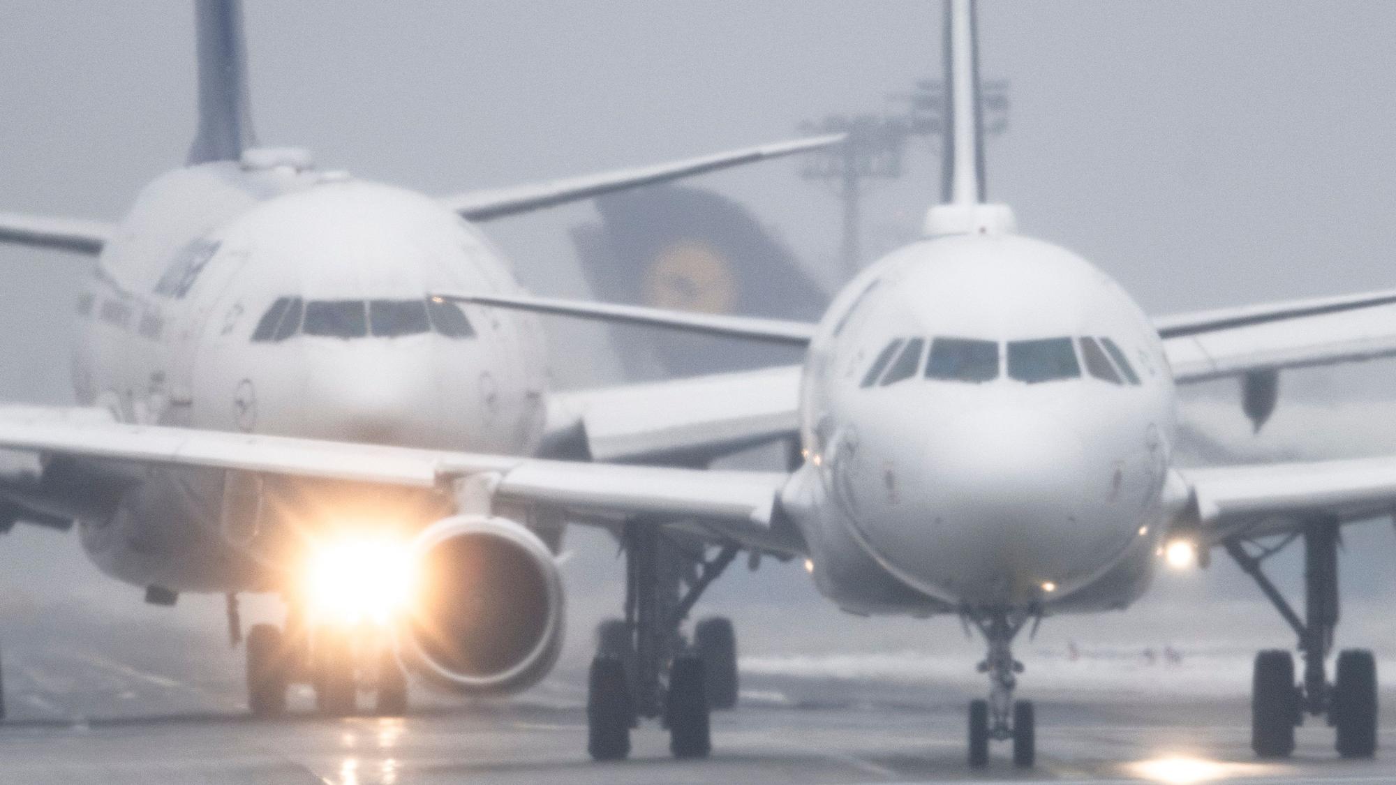 Passagiermaschinen warten bei Sprühregen und Schnee auf dem Flughafen Frankfurt auf ihre Startfreigabe.