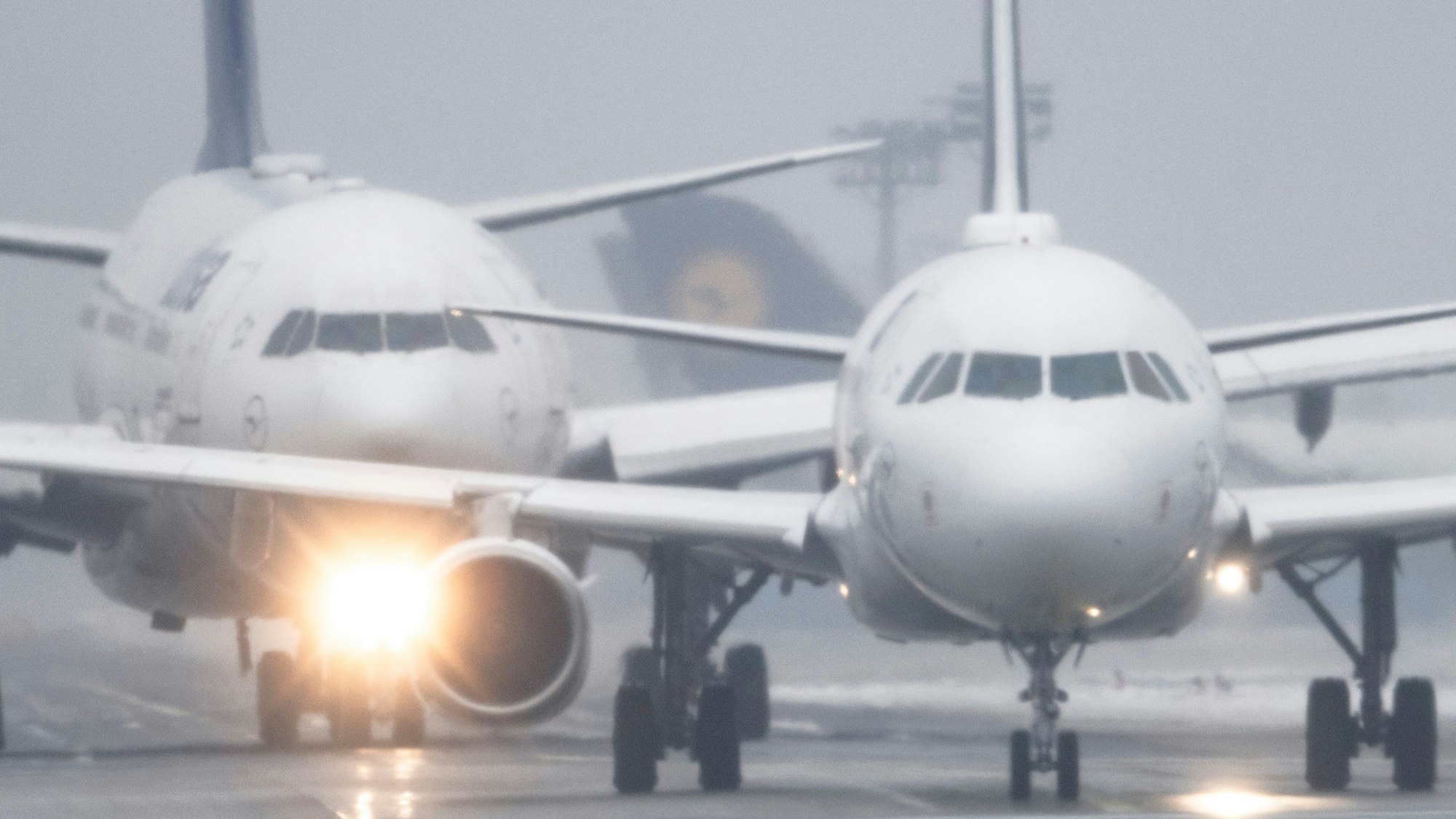 Passagiermaschinen warten bei Sprühregen und Schnee auf dem Flughafen Frankfurt auf ihre Startfreigabe.