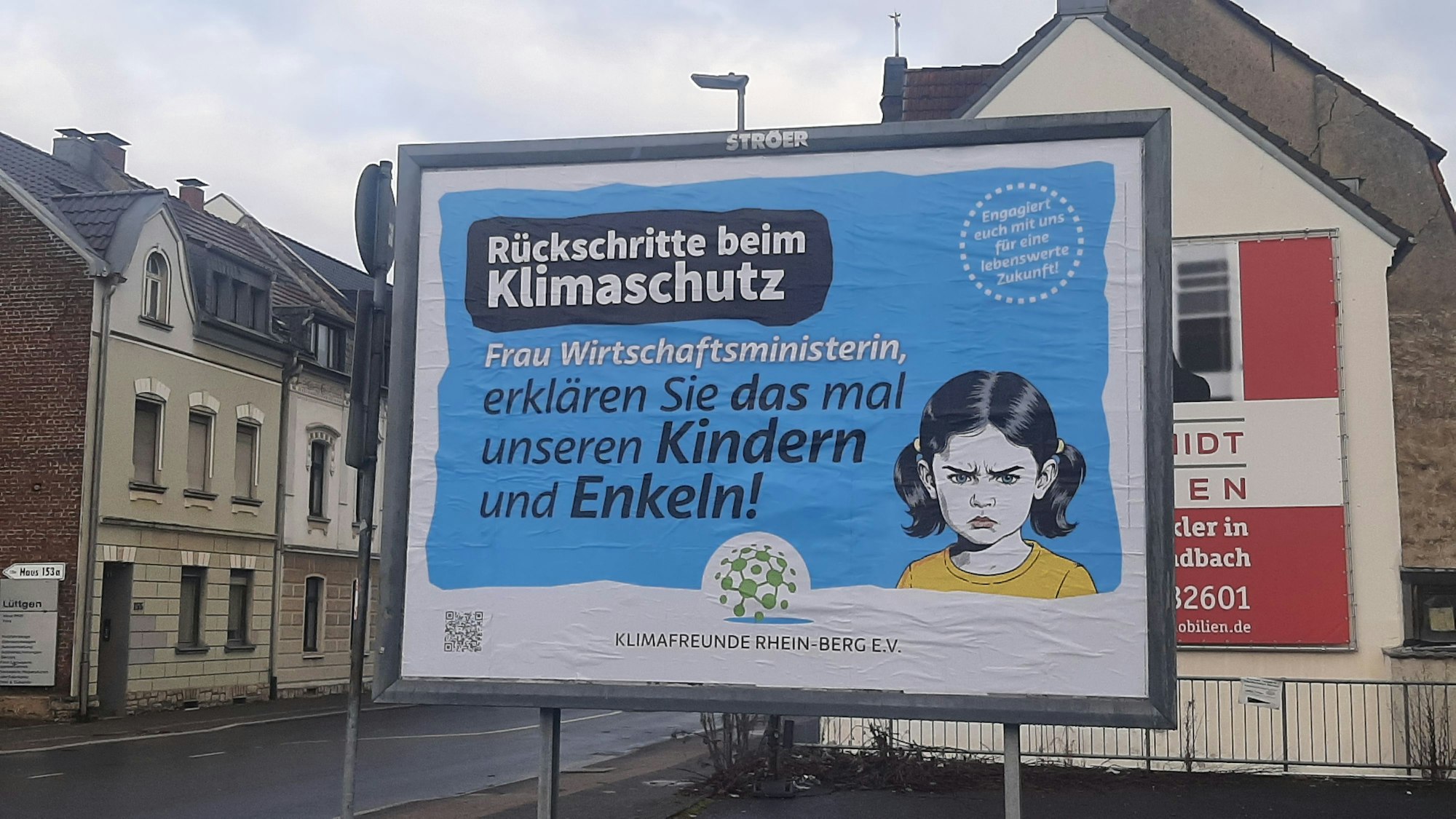 Ein großes Plakat vor einer Hauswand warnt vor Rückschritten beim Klimaschutz.