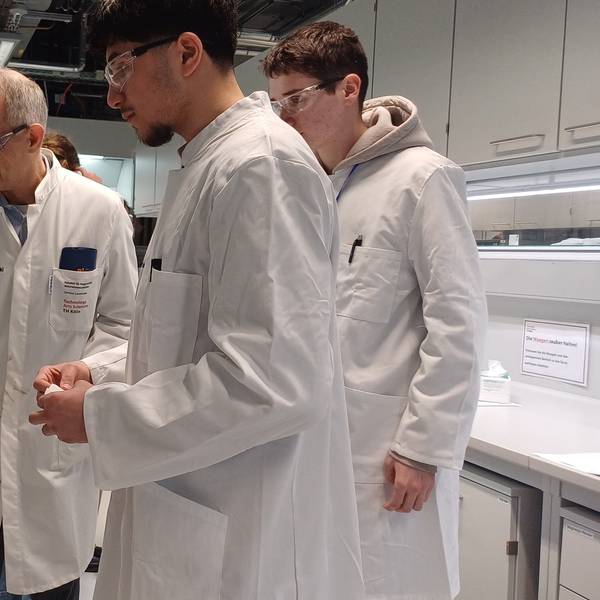 Prof. Dr. Dirk Burdinski zeigt den fluoreszierenden Farbstoff, den zwei Teilnehmer synthetisiert haben.
