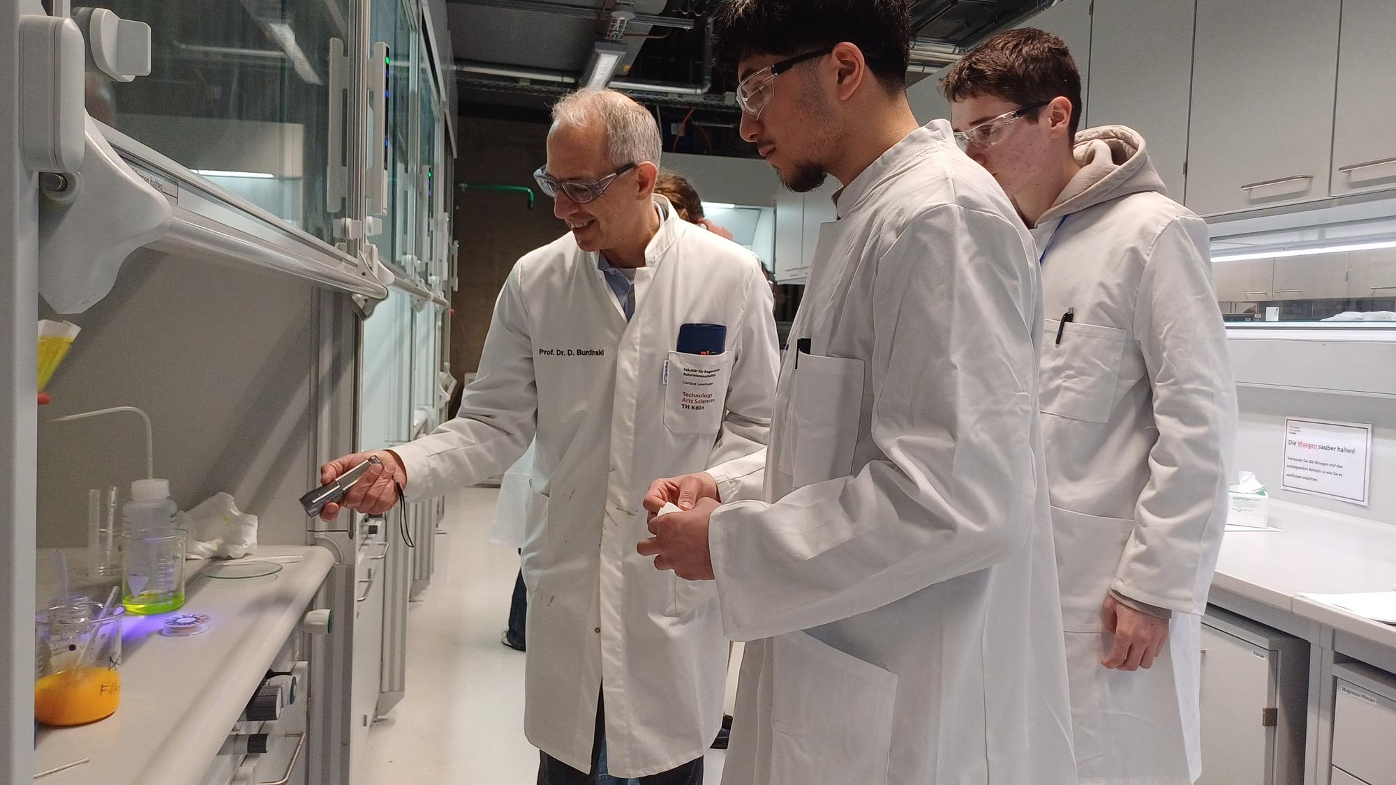 Prof. Dr. Dirk Burdinski zeigt den fluoreszierenden Farbstoff, den zwei Teilnehmer synthetisiert haben.