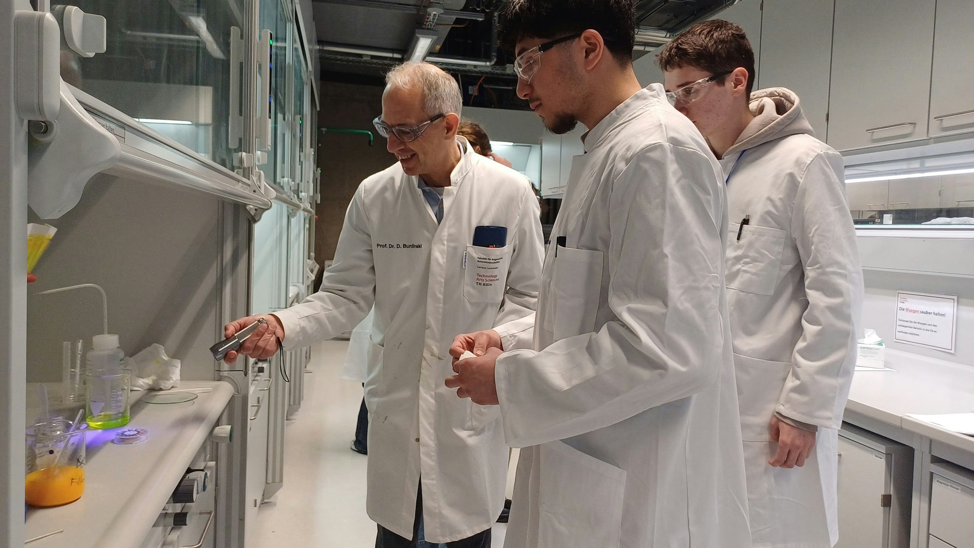 Prof. Dr. Dirk Burdinski zeigt den fluoreszierenden Farbstoff, den zwei Teilnehmer synthetisiert haben.