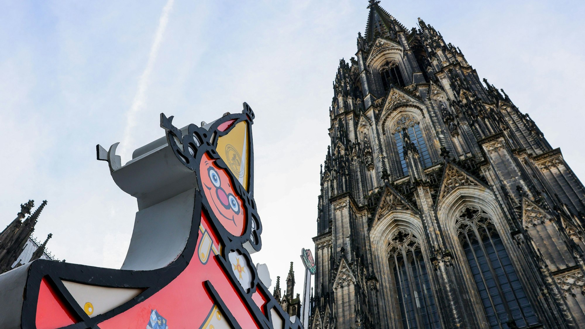 Eine Karnevalsfigur steht vor dem Dom.
