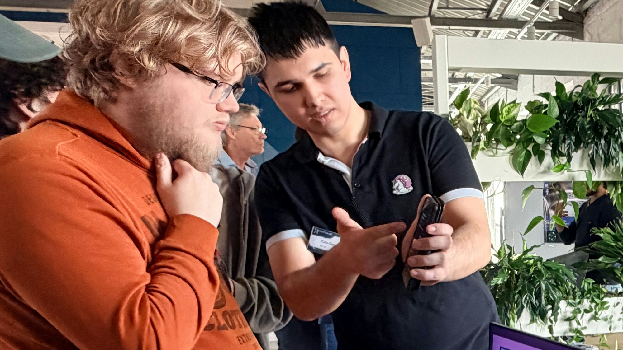 Ein junger Mann zeigte einem interessierten Besucher auf seinem Handy die Funktion der App.