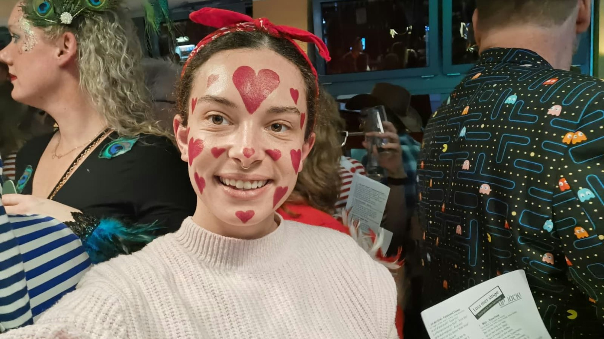 Eine Frau mit Herzen ins Gesicht gemalt lächelt in die Kamera.