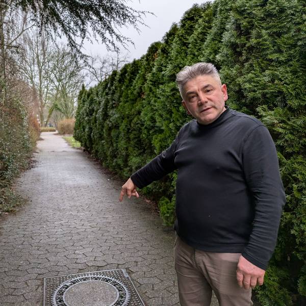 Samet Dzeladini, Eigentümer der Stadthalle Bergisch Neukirchen, weist auf einen der Kanaldeckel, die bei starkem Regen vom Wasser hochgedrückt werden.