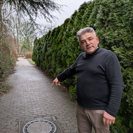 Samet Dzeladini, Eigentümer der Stadthalle Bergisch Neukirchen, weist auf einen der Kanaldeckel, die bei starkem Regen vom Wasser hochgedrückt werden.