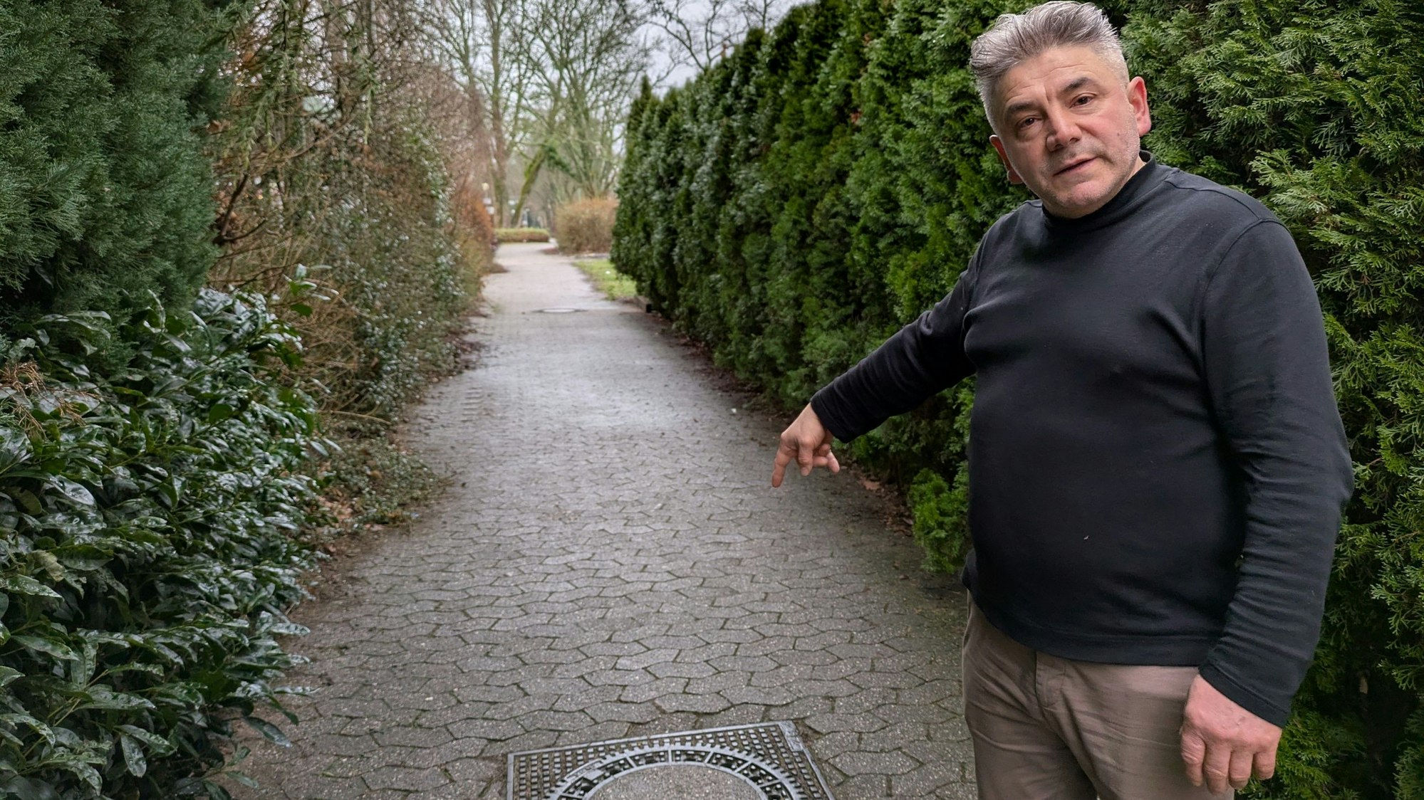 Samet Dzeladini, Eigentümer der Stadthalle Bergisch Neukirchen, weist auf einen der Kanaldeckel, die bei starkem Regen vom Wasser hochgedrückt werden.