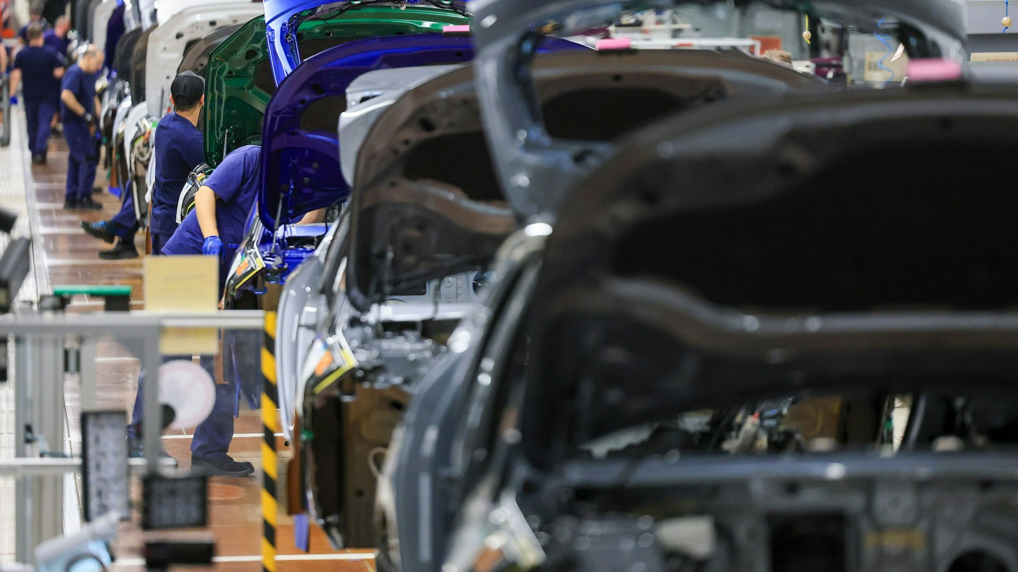 Mitarbeiter im BMW Group Werk Leipzig arbeiten an einer Montagelinie.