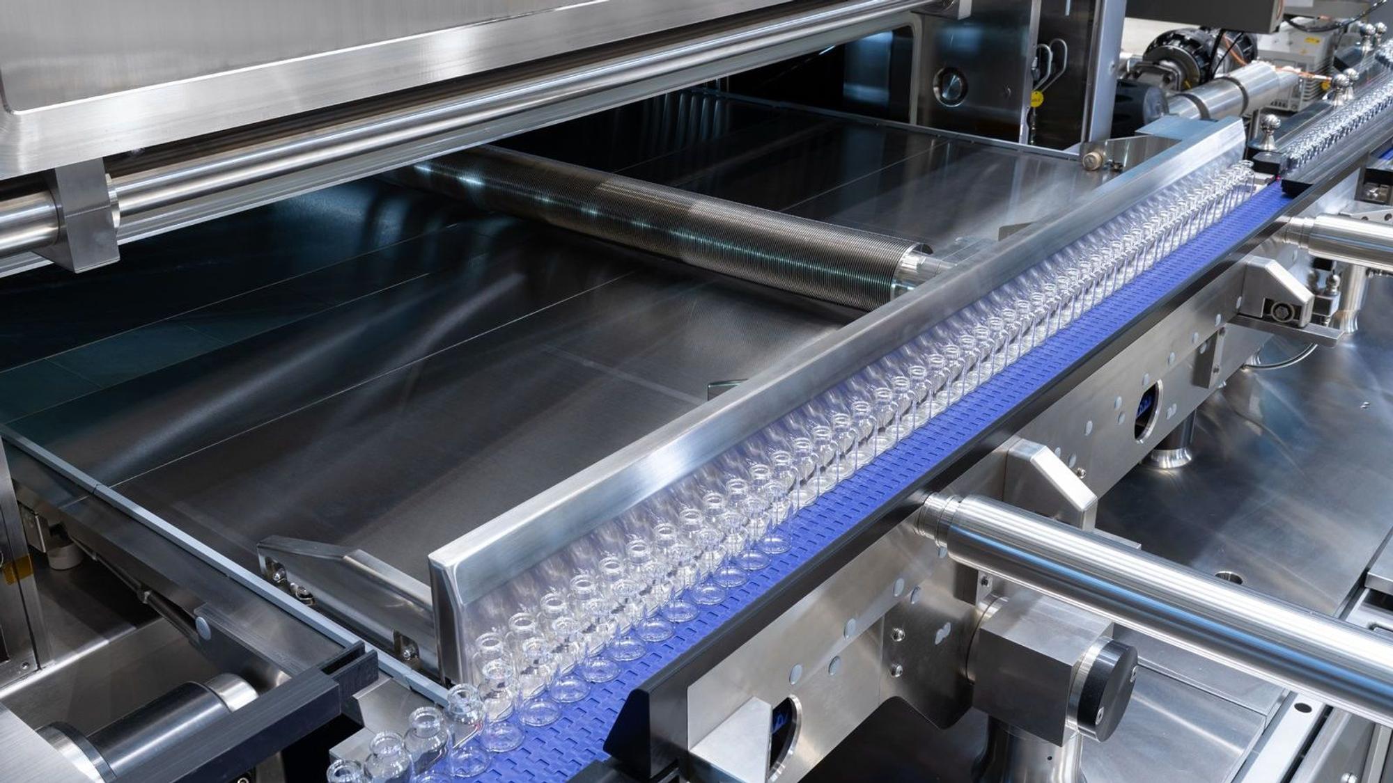 Glasfläschchen, in die Impfstoffe abgefüllt werden, laufen über ein automatisches Transportsystem von Gea.