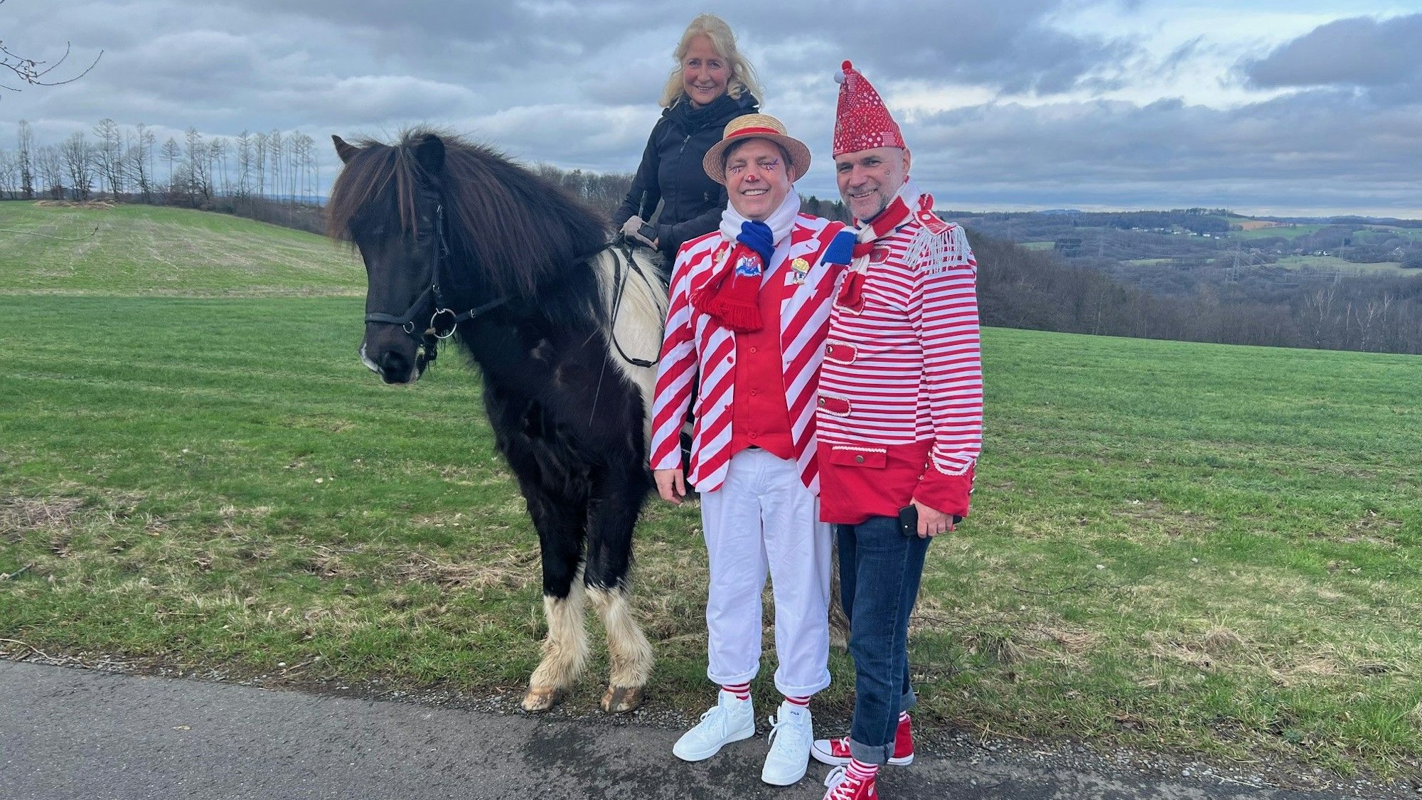 Karneval in rut un wiess: Ehepaar Peter Ströhmer mit Mann Burkhard ist ins Oberbergische gezogen. Sie trafen unterwegs auf Freundin Uta mit Pferd. Sie pflegen das Brauchtum trotz Köln-Flucht.