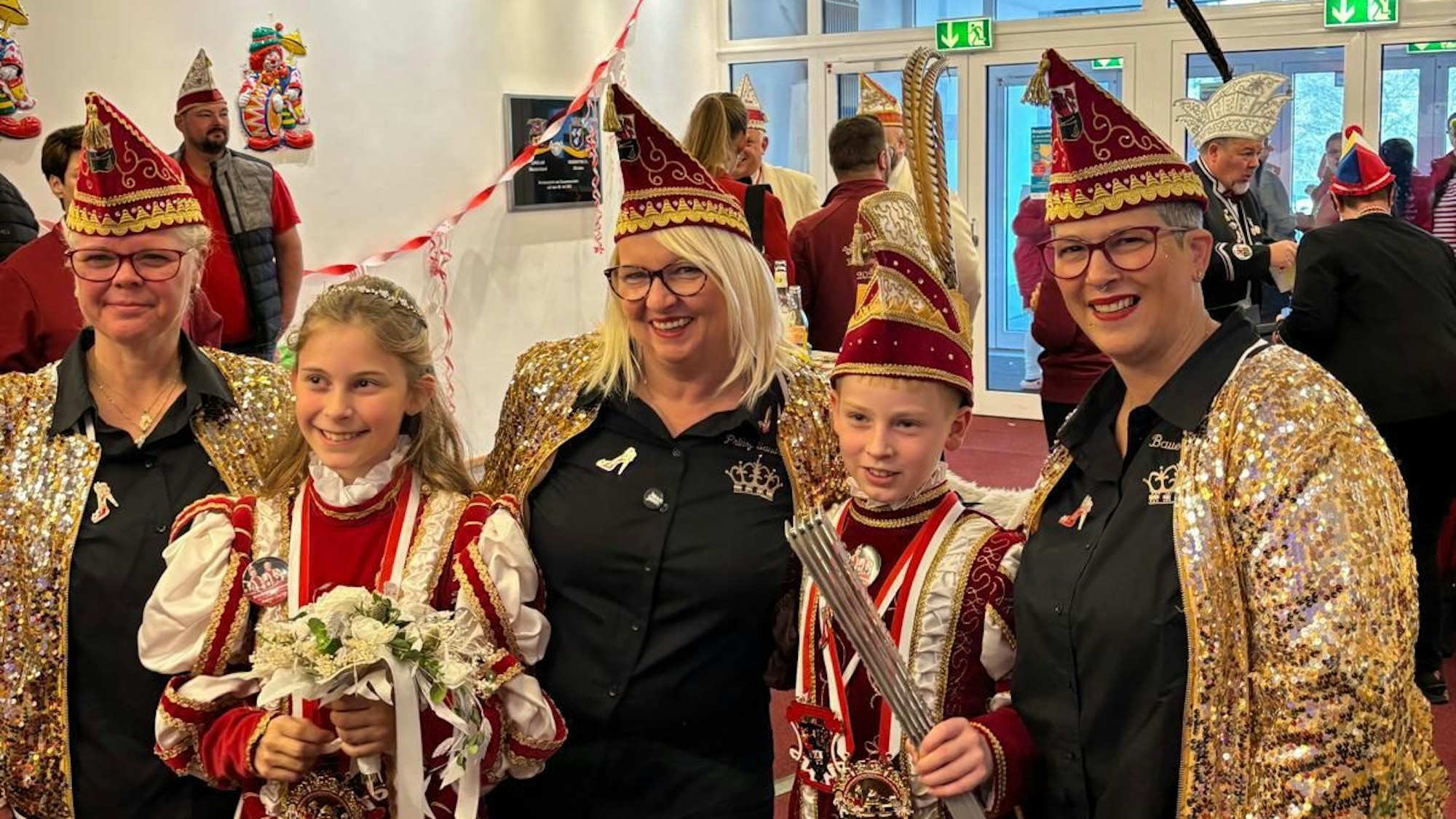 Ein Dreigestirn und ein Kinderprinzenpaar stehen beisammen.