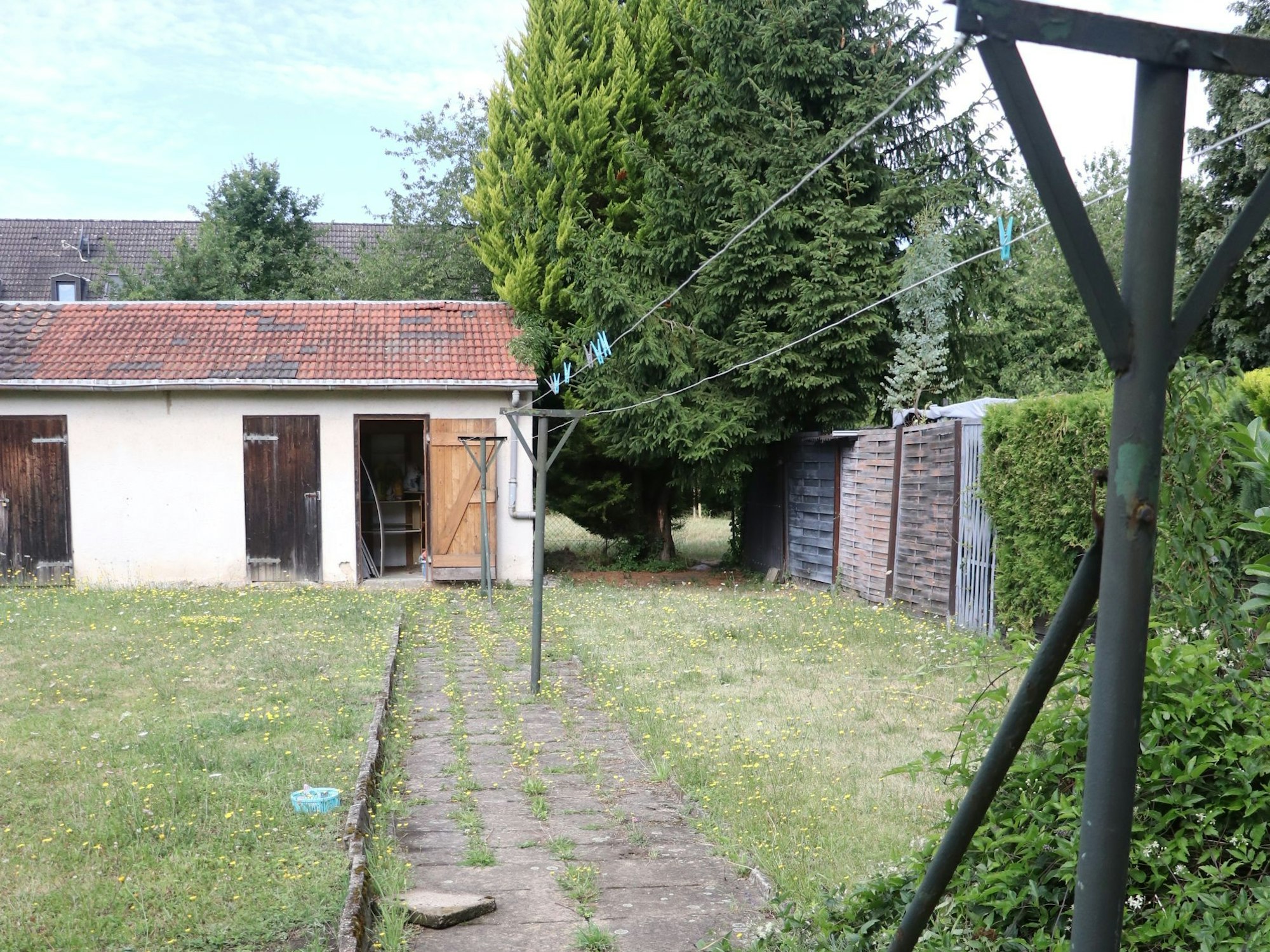 Auf dem Bild ist ein alter Schuppen in einem Garten zu sehen.