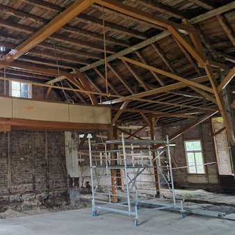 Zu sehen ist ein entkernter Saal, dessen Wände mit Fachwerk gebaut sind.