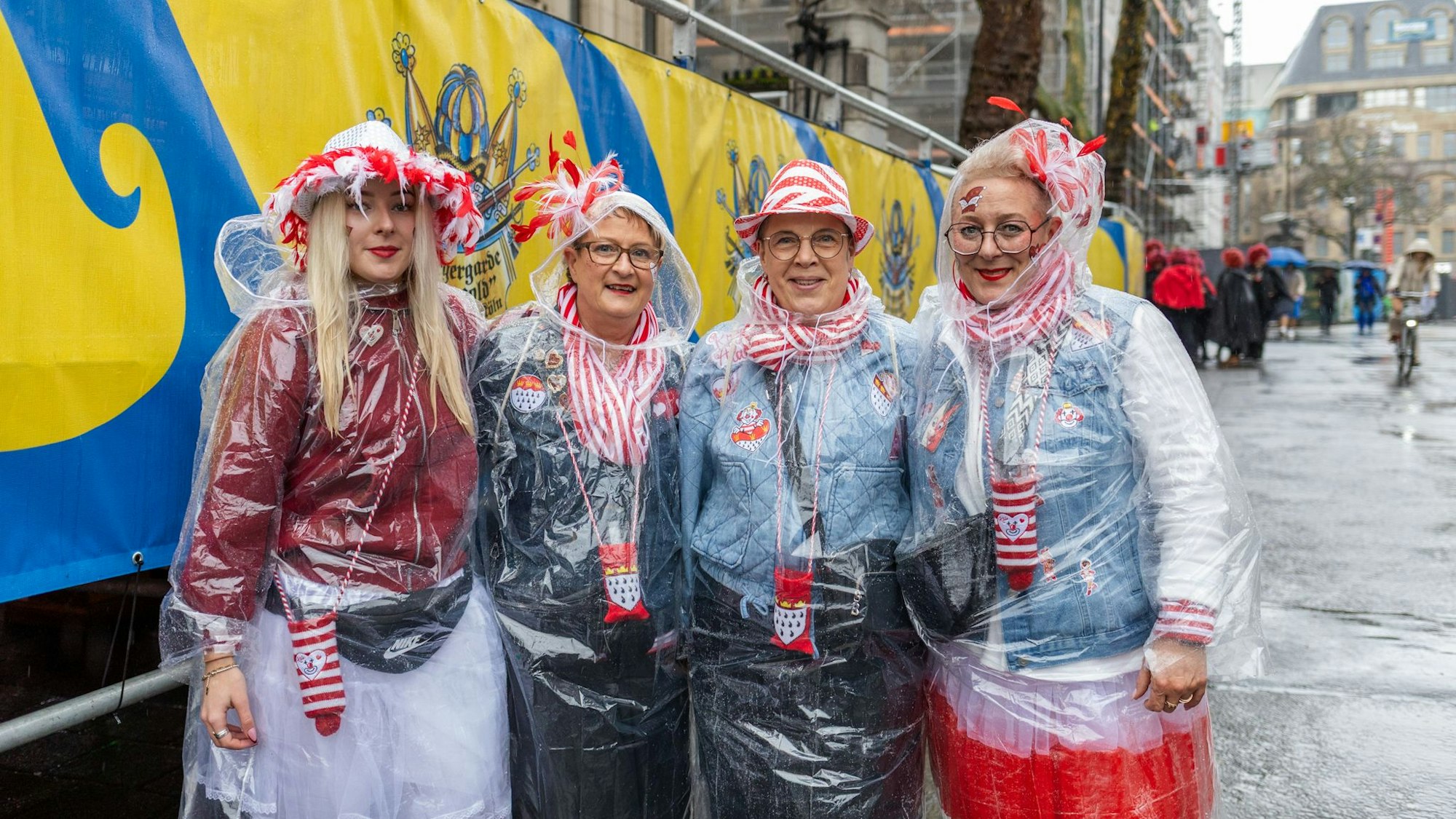 Vier Frauen in Rot und Weiß mit Regenponcho.