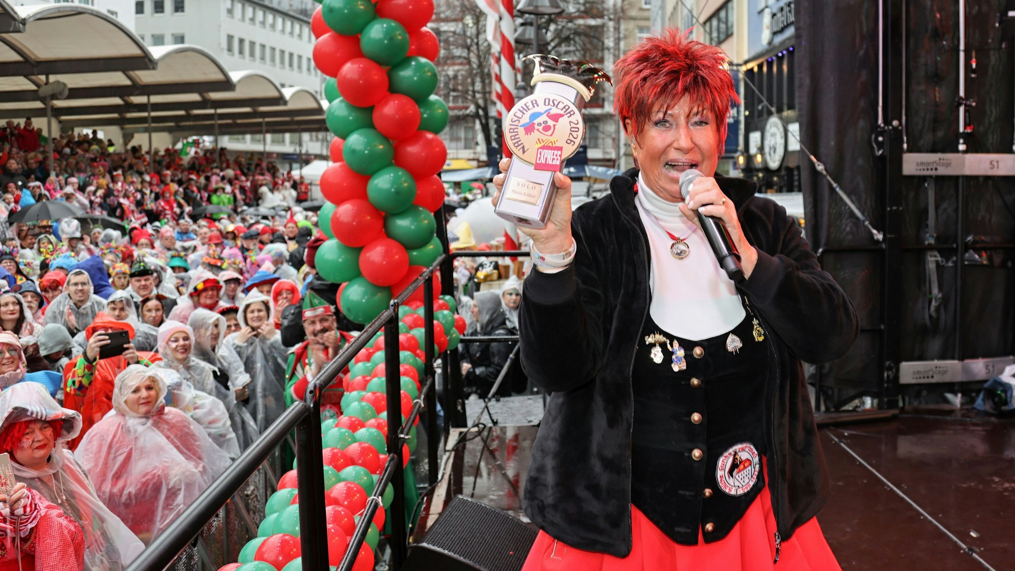 Kurz vor dem Sturz: Stolz zeigt Marita Köllner am Donnerstag (12. Februar 2026) den Närrischen Oscar auf der Bühne am Alter Markt.