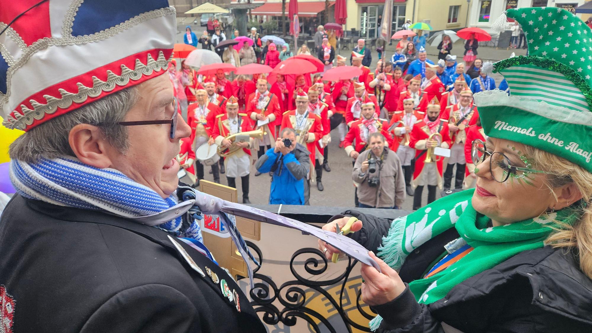 Barbara Sieger von der Katholischen Frauengemeinschaft schneidet Bedburgs Bürgermeister Sascha Solbach den Schlips ab.