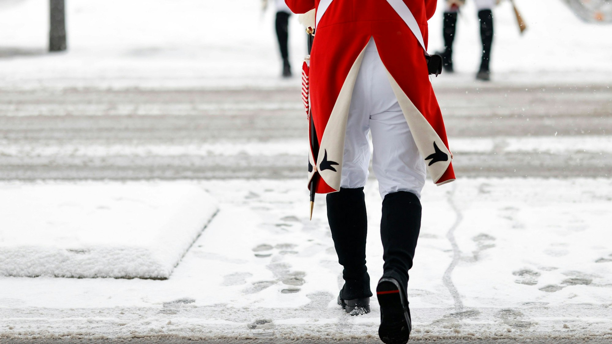 Ein Karnevalist der Roten Funken gehen durch das Schneetreiben.