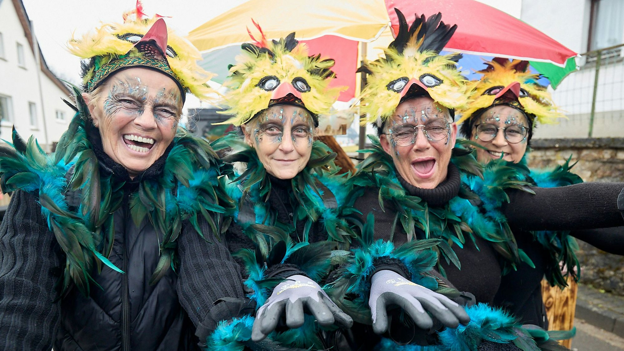 Vier Frauen sind als Hühner verkleidet und tragen ein buntes Federkleid.