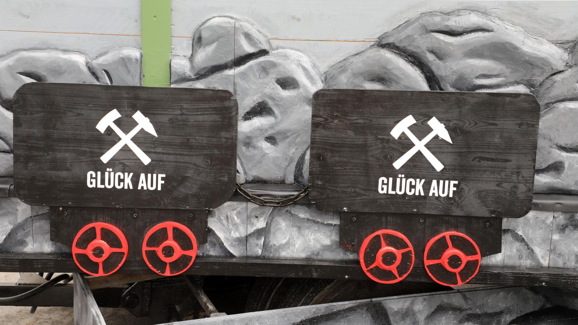 Zwei schwarze Loren, Förderwagen, in denen Erz transportiert wurde, mit Bergbau-Logo und je zwei roten Rädern wurden am unteren Teil des Wagens nachgebildet.