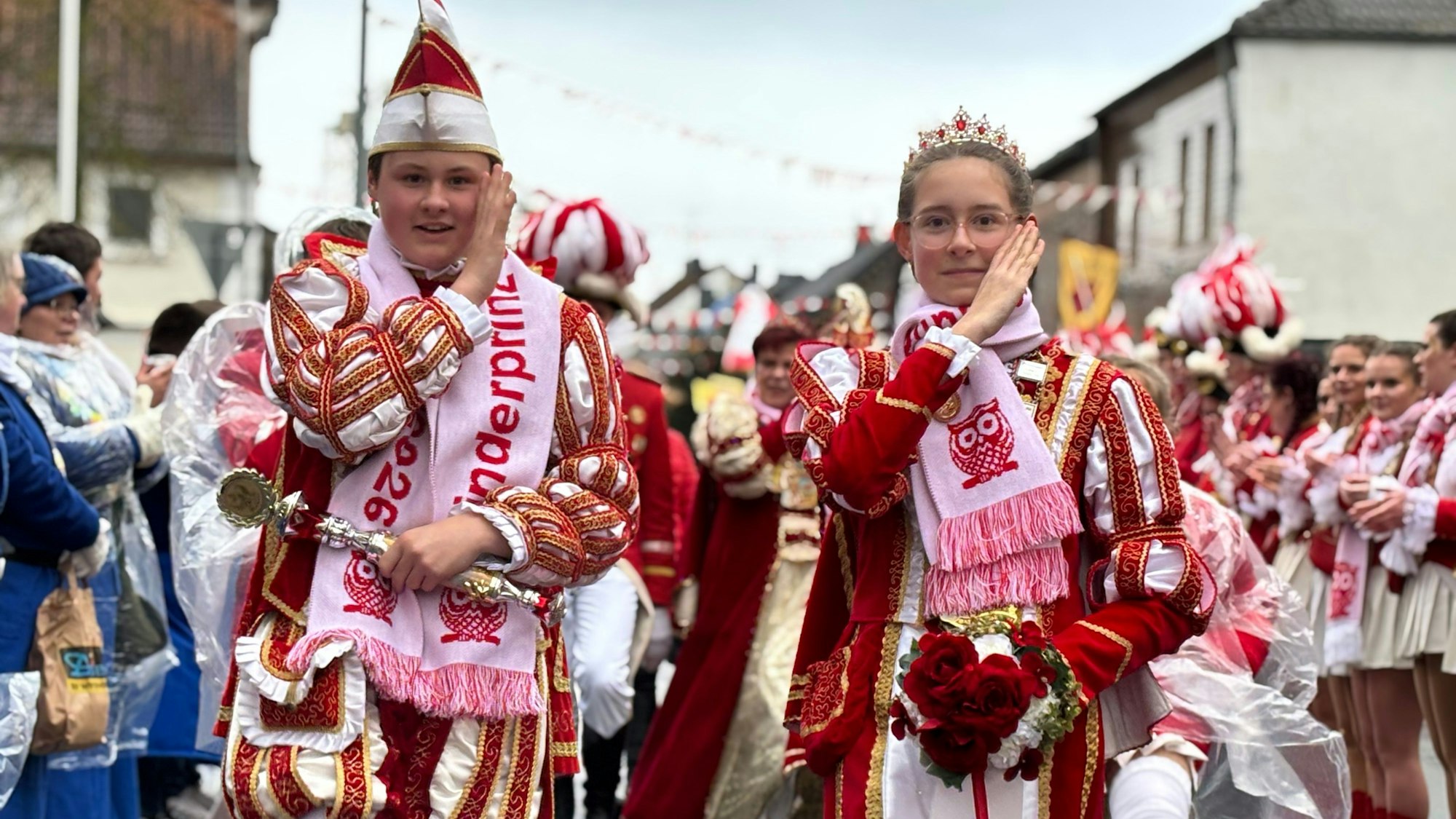Das Kinderprinzenpaar Julian II. und Leonie I. grüßt karnevalistisch mit der Hand an der Schläfe.