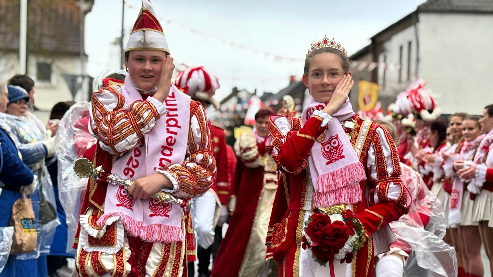 Das Kinderprinzenpaar Julian II. und Leonie I. grüßt karnevalistisch mit der Hand an der Schläfe.