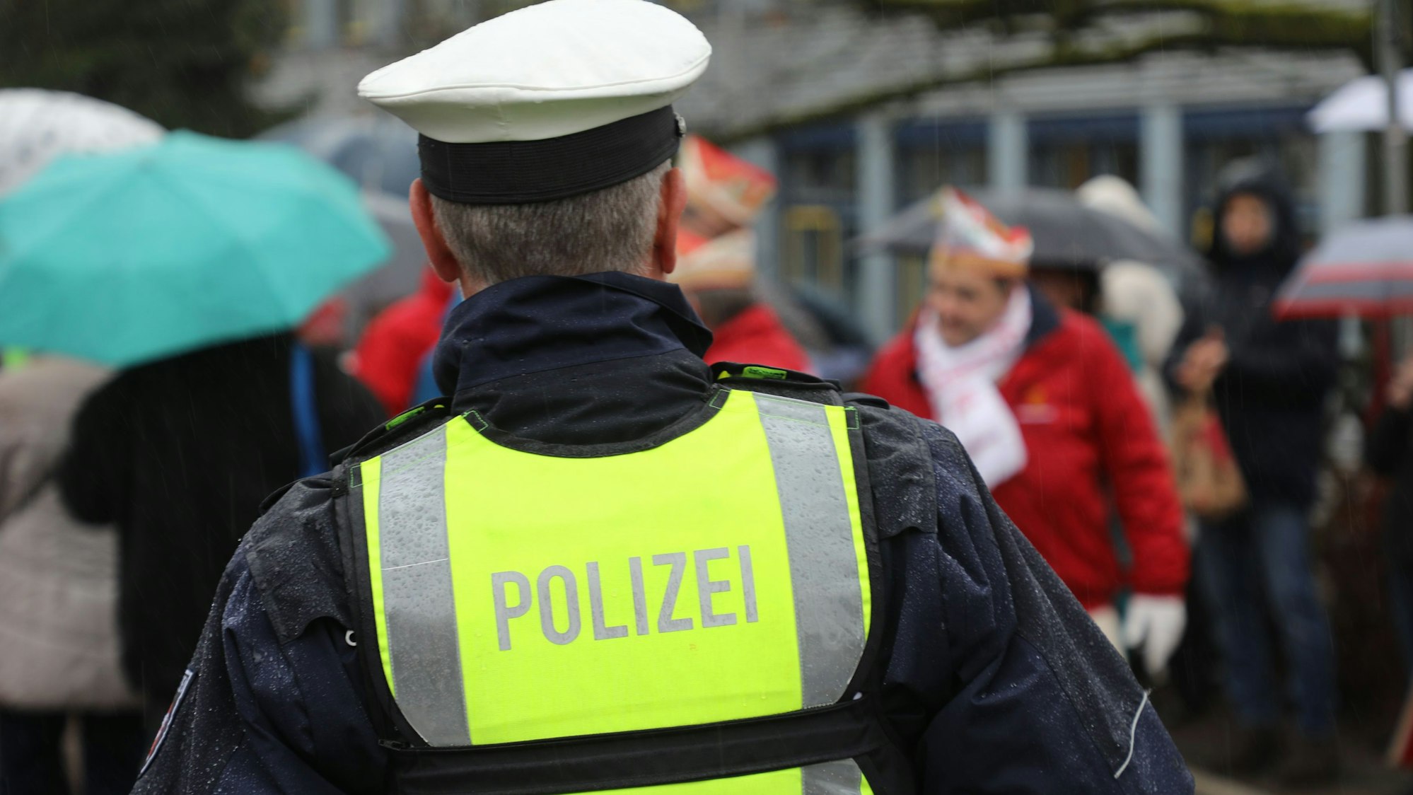 Ein Polizist beobachtet eine Gruppe von Karnevalisten.