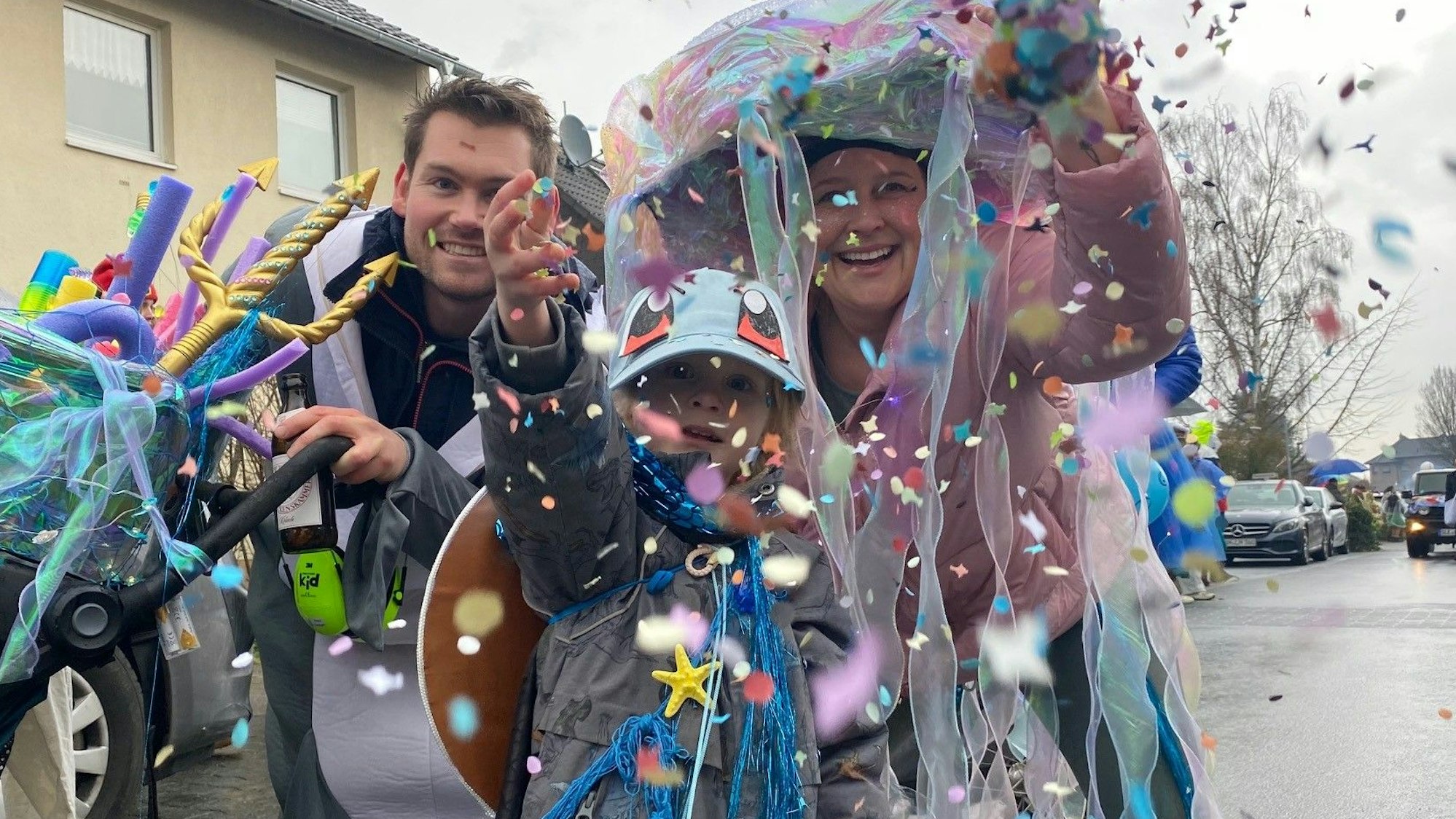 Eine Frau, ein Mann und ein Junge werfen Konfetti.