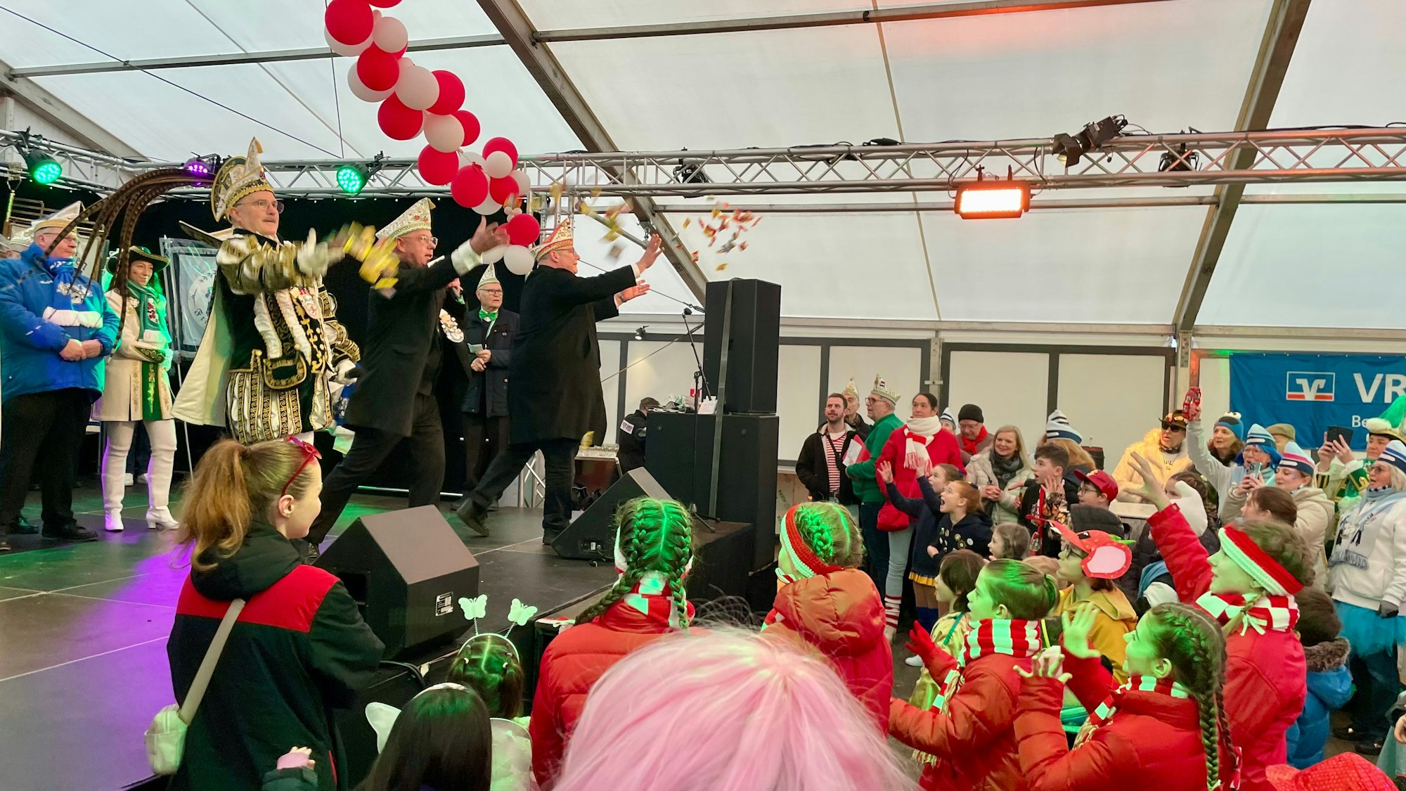 Der Straßenkarneval in Opladen ist eröffnet: Prinz Rogério, KOK-Präsident Peter Rösgen und OB Stefan Hebbel werfen Kamelle in die Menge.