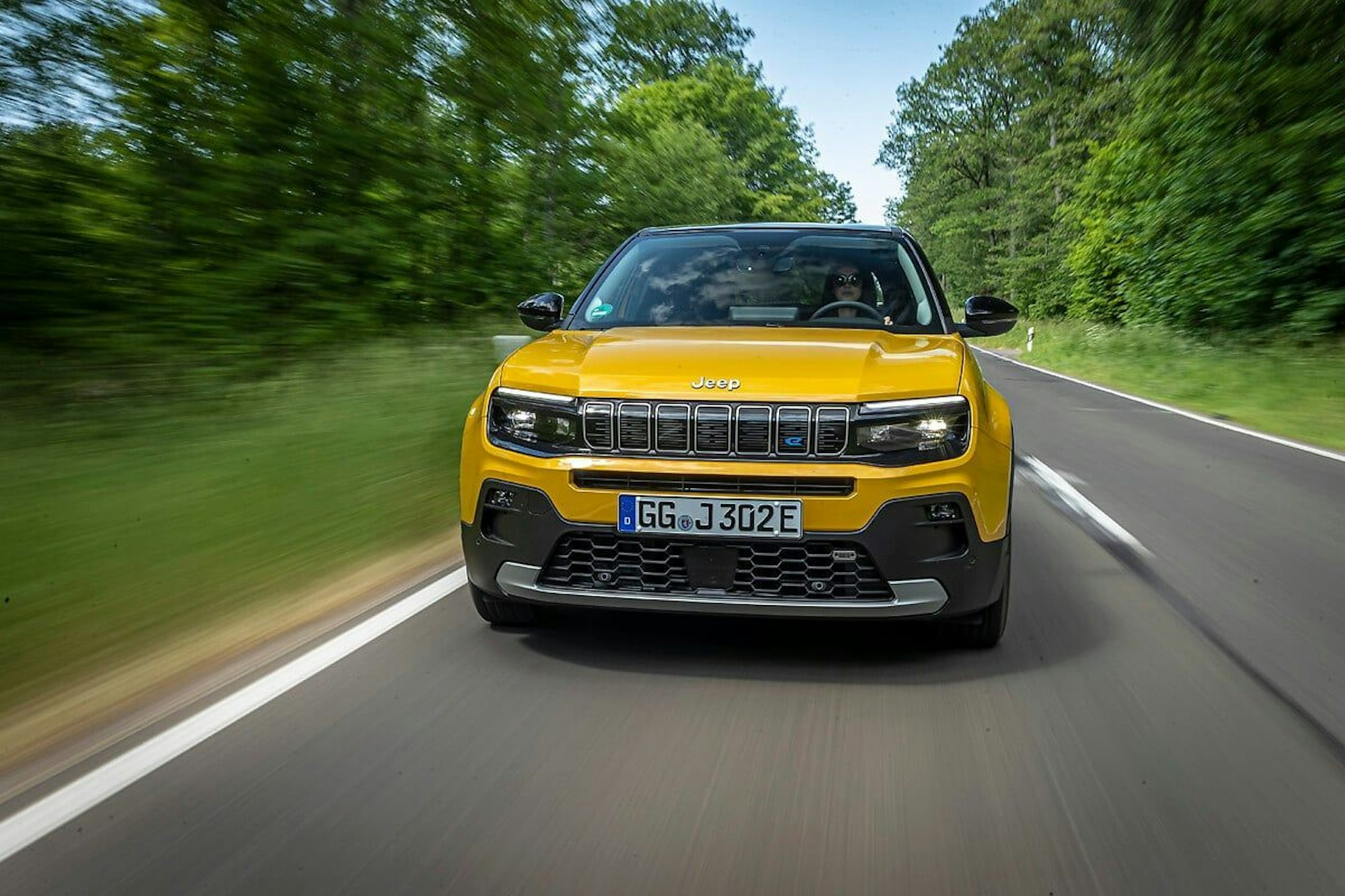 Ein gelber Jeep Avenger fährt auf einer Straße.