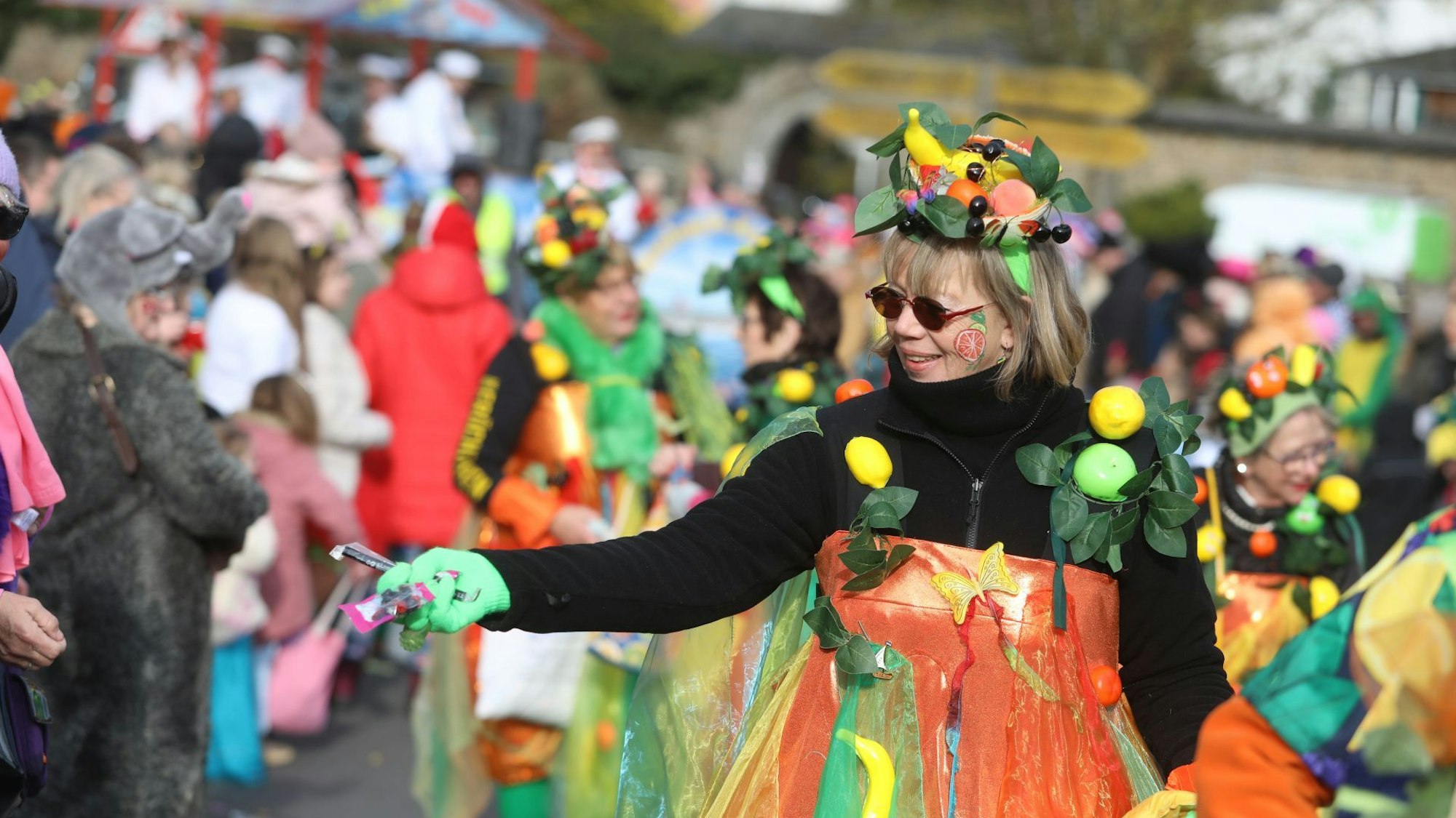 Eine bunt kostümierte Frau verteilt Kamelle.