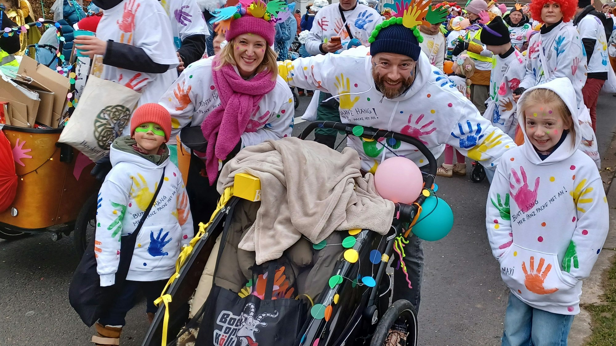 Kinder mit Hoodies, auf denen bunte Handabdrücke sind, laufen im Zoch mit.