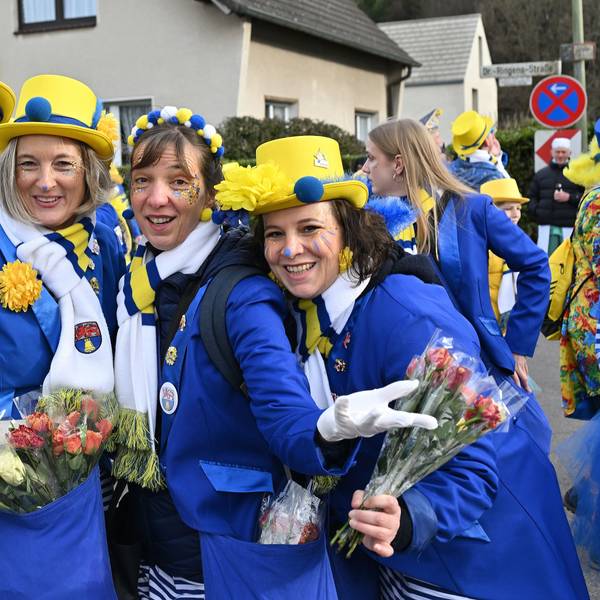 Eine Gruppe Karnevalisten trägt einen blau-gelben Anzug und hat Strüssjer und eine Flasche Bier dabei.