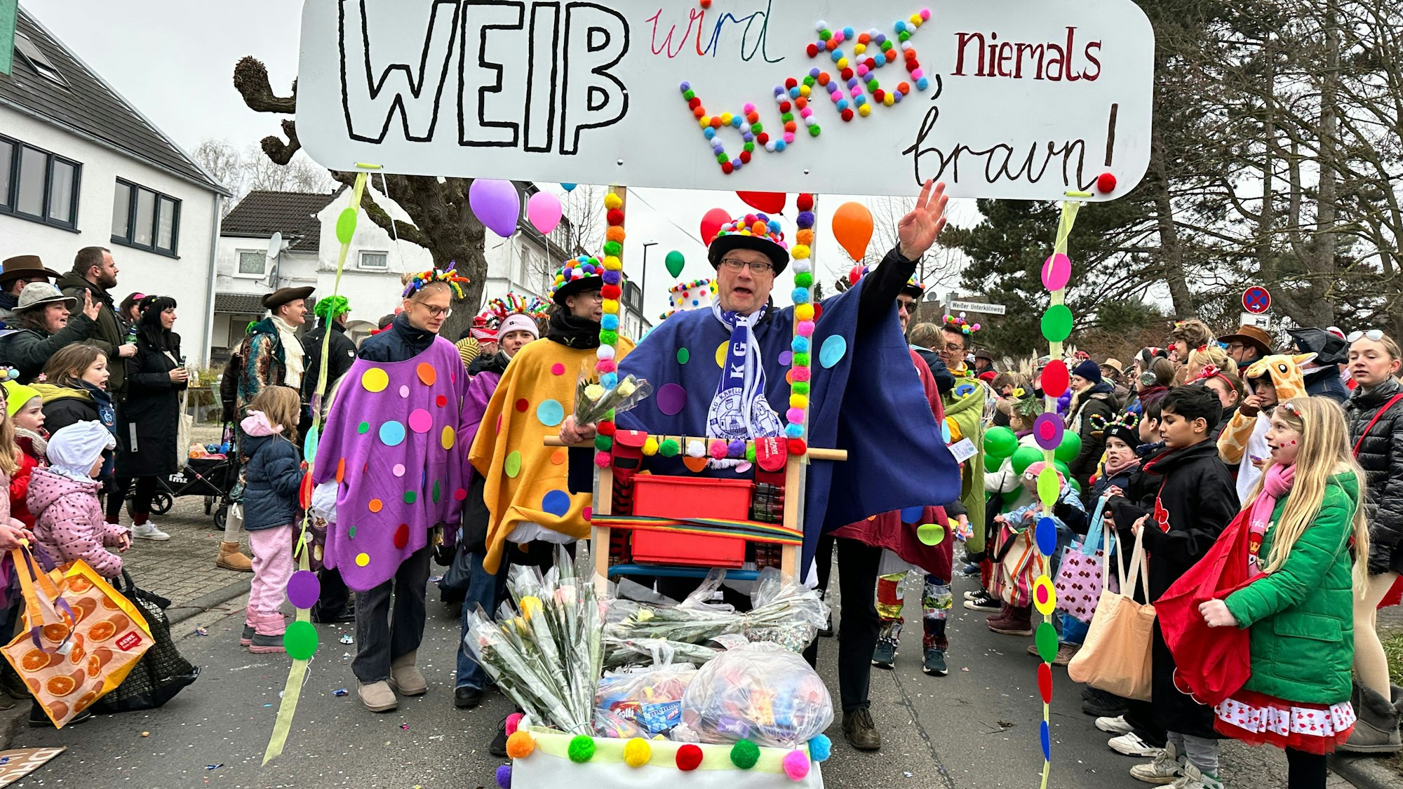 Eine Fußgruppe läuft mit einem Schild durch eine Straße: Weiß wird bunt, niemals braun.