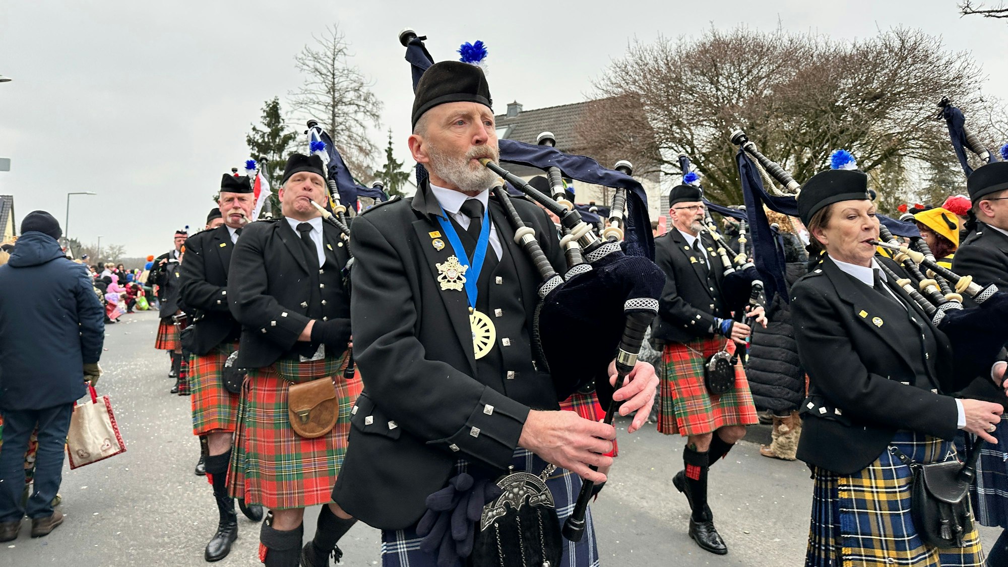 Eine Gruppe in schottischen Kilts und mit Dudelsäcken läuft durch eine Straße.