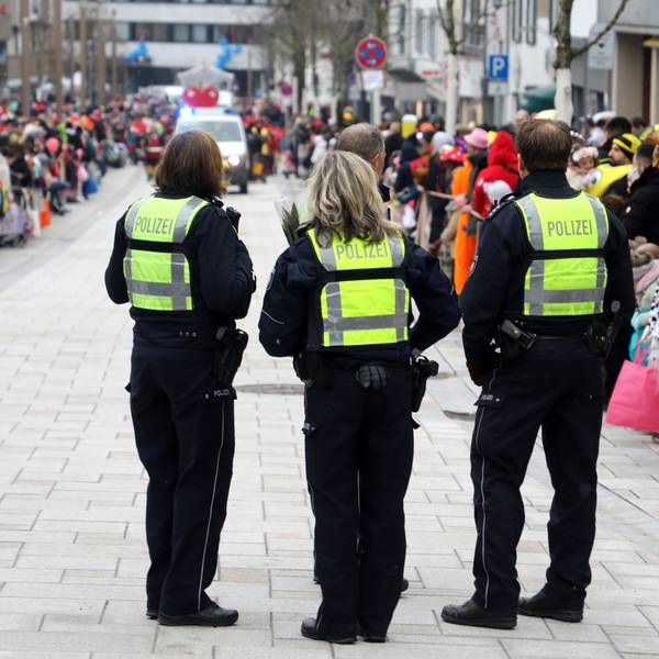 Polizeibeamtinnen und -beamte stehen vor dem Karnevalszug in der Bensberger Schloßstraße.