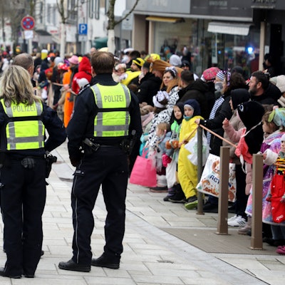 Polizeibeamtinnen und -beamte stehen vor dem Karnevalszug in der Bensberger Schloßstraße.