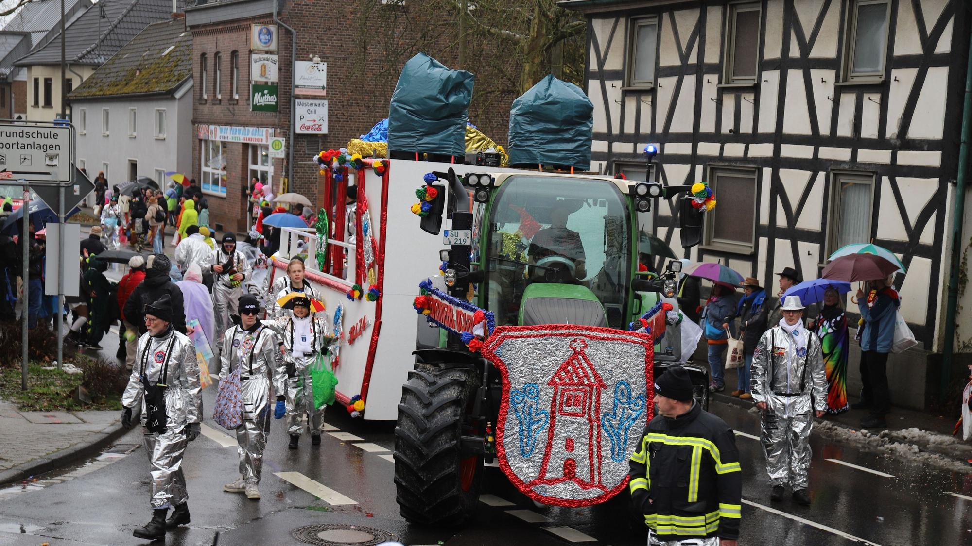 Der Festwagen der Freiwilligen Feuerwehr nimmt die Kurve auf die L 268 Richtung Süchterscheid, die Wagenengel in Silber.