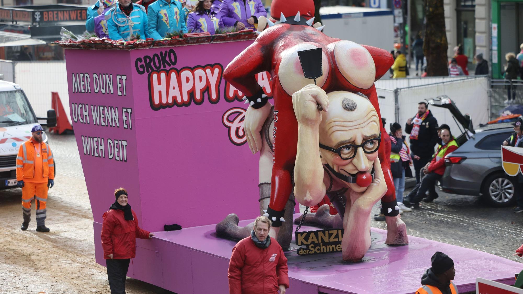 Ein Motivwagen, der Bundeskanzler Merz und Finanzminister Klingbeil bei einer „Sado-Maso-Regierungs-Show“ zeigen, nimmt am Rosenmontagszug in Köln teil.