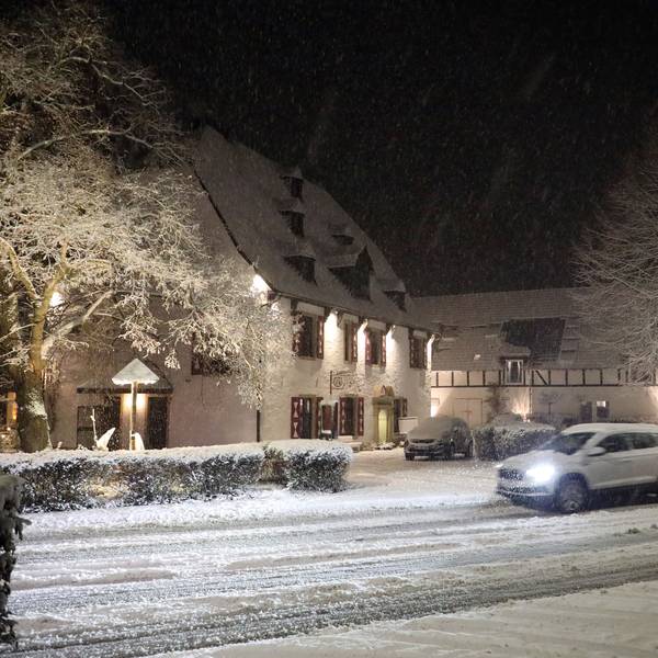 Ein Auto fährt auf einer schneebedeckten Straße an der Malteser Komturei in Bergisch Gladbach-Herrenstrunden vorbei.